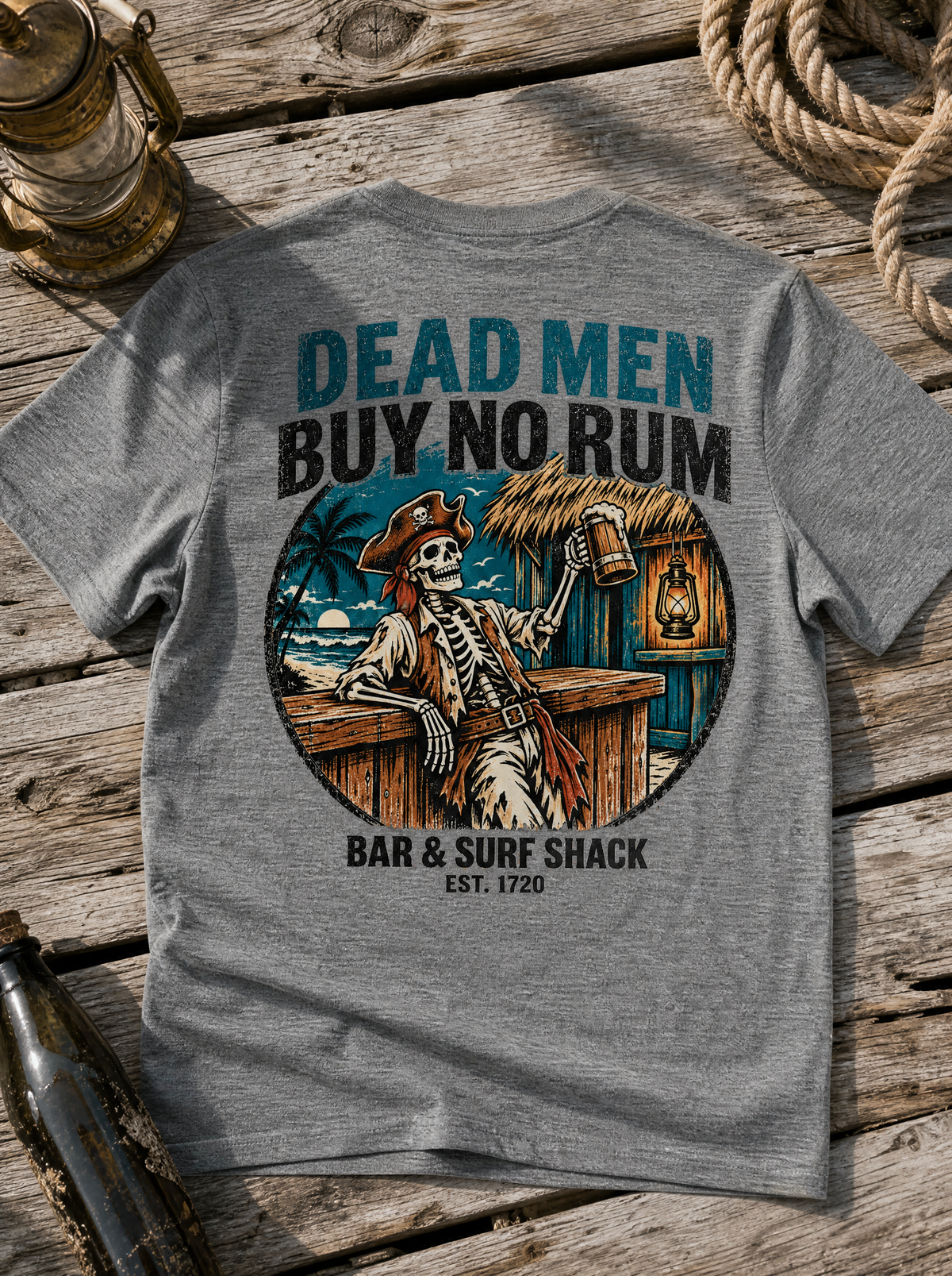 Dead Men Buy No Rum Deep Heather tee flat lay on weathered driftwood with rope and ship lantern