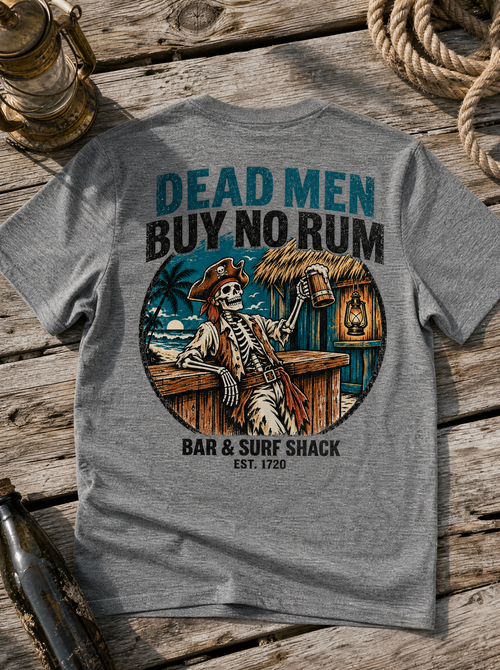 Dead Men Buy No Rum Deep Heather tee flat lay on weathered driftwood with rope and ship lantern